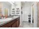 Bathroom with double vanity, gray countertop, storage shelves, and tiled floor at 6357 Shore Vista Pl, Apollo Beach, FL 33572