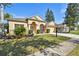 Charming single-story home featuring an arched entryway, lush landscaping, and attached garage at 1130 Big Creek Dr, Wesley Chapel, FL 33544