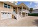 Beautiful beige home with two garages, one under the house and another next to the entrance at 210 Lakeview Dr, Anna Maria, FL 34216