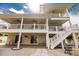 Spacious home exterior with a lower-level patio, second-story balcony, and lush landscaping, creating a serene waterfront lifestyle at 210 Lakeview Dr, Anna Maria, FL 34216