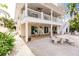 Beautiful waterfront home with a patio, two chairs, outdoor dining area, and steps up to the balcony above at 210 Lakeview Dr, Anna Maria, FL 34216