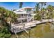 Stunning waterfront home featuring balconies, a private dock, and lush tropical landscaping at 210 Lakeview Dr, Anna Maria, FL 34216