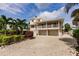 View of a two-story beige house, including the garage and access to the main floor by stairs at 210 Lakeview Dr, Anna Maria, FL 34216