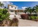 Beautiful two-story home with a beige exterior, white trim, and well-manicured landscaping with palm trees at 210 Lakeview Dr, Anna Maria, FL 34216