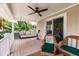 Covered patio with a porch swing, wicker seating, ceiling fan, and beautiful views of tropical foliage at 210 Lakeview Dr, Anna Maria, FL 34216