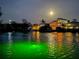 Night view of waterfront homes under moonlight, featuring dock lights reflecting on the tranquil water and well-lit exteriors at 210 Lakeview Dr, Anna Maria, FL 34216