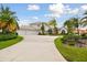Beautiful waterfront home boasts a three-car garage, mature palms, and circular driveway on a sunny day at 5709 E Longboat Blvd, Tampa, FL 33615