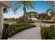 Professionally landscaped front yard with palms, colorful flowers, and serene water views from the front porch at 5709 E Longboat Blvd, Tampa, FL 33615