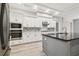 Modern kitchen with gray island, white cabinets, and stainless steel appliances at 19411 Sheltered Hill Dr, Brooksville, FL 34601