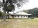 Rear exterior view showing a well-maintained single-story house with a spacious backyard at 30737 Elam Rd, Wesley Chapel, FL 33545