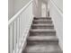 Modern staircase with white railings and grey carpeting at 1653 Ludington Ave, Wesley Chapel, FL 33543