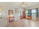 Bright living room features light wood floors, fan, and large windows with curtains at 13939 Swallow Hill Dr, Lithia, FL 33547
