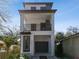 Modern three-story home featuring a balcony, one-car garage, and a sleek white facade at 1734 W Cherry St, Tampa, FL 33607