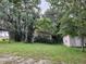 Tan colored house with partial view of a shed in wooded area at 15222 Lost Lake Ln, Lithia, FL 33547