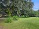 Backyard with flower garden and large oak trees at 15222 Lost Lake Ln, Lithia, FL 33547