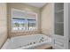 Bathroom featuring a large soaking tub and pool view at 9506 Pebble Glen Ave, Tampa, FL 33647