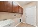 Laundry room with wooden cabinets, utility sink, and vinyl flooring at 5321 Silver Charm Ter, Wesley Chapel, FL 33544