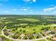 Expansive aerial view of a residential area integrated with a lush green golf course and a wooded landscape at 13049 Thoroughbred Dr, Dade City, FL 33525