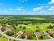 High aerial view showcasing homes situated along a golf course and woodlands, under a partly cloudy sky at 13049 Thoroughbred Dr, Dade City, FL 33525