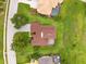 Aerial view of a home with a brown roof, surrounded by lush greenery and well-maintained lawns and neighboring homes at 13049 Thoroughbred Dr, Dade City, FL 33525