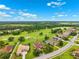 Overhead aerial view of homes located by a golf course, with distant views of a lush, green wooded area at 13049 Thoroughbred Dr, Dade City, FL 33525