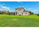 Exterior of home featuring two-story design, covered lanai and balcony, with a lush green lawn at 13049 Thoroughbred Dr, Dade City, FL 33525