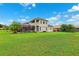 Large green backyard with a two-story home, screened lanai and open balcony overlooking the grounds at 13049 Thoroughbred Dr, Dade City, FL 33525