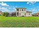 Spacious backyard featuring a screened lanai, lush green lawn, and a view of the two-story home at 13049 Thoroughbred Dr, Dade City, FL 33525