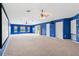 Large bonus room with blue walls, carpet flooring, multiple windows, and a ceiling fan at 13049 Thoroughbred Dr, Dade City, FL 33525