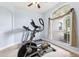 Bright exercise room featuring an elliptical machine, treadmill, and a large window with draperies at 13049 Thoroughbred Dr, Dade City, FL 33525