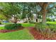 View of the home's manicured front yard, with mature trees and lush greenery at 13049 Thoroughbred Dr, Dade City, FL 33525