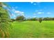 Beautifully manicured golf course with lush green grass and mature trees under a bright blue sky with scattered clouds at 13049 Thoroughbred Dr, Dade City, FL 33525