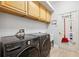 Laundry room boasts wood cabinets, modern washer and dryer, utility sink and access to the garage at 13049 Thoroughbred Dr, Dade City, FL 33525