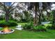 Relaxing backyard with fire pit, seating, and hammock under large trees at 3111 Arrowsmith Rd, Wimauma, FL 33598