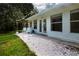 Whitewashed patio with metal chairs and string lights, adjacent to house and wooded area at 3111 Arrowsmith Rd, Wimauma, FL 33598