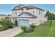 Two-story house with a light-blue garage door, landscaping, and a metal roof at 30425 Pecan Valley Loop, Wesley Chapel, FL 33543