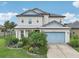 Two-story house with a light-blue garage door, landscaping, and a metal roof at 30425 Pecan Valley Loop, Wesley Chapel, FL 33543