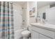 Clean bathroom with tub shower, white vanity, and striped shower curtain at 7864 Broad Pointe Dr, Zephyrhills, FL 33540
