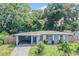 Charming single-story home with carport and front lawn, surrounded by lush trees and a partial fence at 1611 Stevenson Dr, Clearwater, FL 33755
