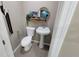 Compact half-bathroom featuring a pedestal sink, toilet, and decorative mirror at 8013 N Ola Ave, Tampa, FL 33604
