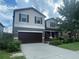 Two-story house with brown garage door and landscaping at 3015 Winglewood Cir, Lutz, FL 33558