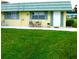 Front view of a yellow single-story home with green roof and small lawn at 102 Cambridge Trl # 230, Sun City Center, FL 33573