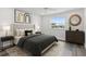 Comfortable bedroom with a plush bed, stylish lamps, wood-look floors, and sun-filled window with an outdoor view at 8716 Elmwood Ln, Tampa, FL 33615