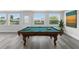 Bright game room featuring a pool table, gray wood floors, and large windows offering serene outdoor views at 8716 Elmwood Ln, Tampa, FL 33615