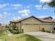 Tan villa with two-car garage, landscaping, and walkway at 227 Mystic Falls Dr, Apollo Beach, FL 33572