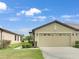 Tan villa with two-car garage, landscaping, and walkway at 227 Mystic Falls Dr, Apollo Beach, FL 33572