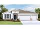 One-story home with white exterior, three-car garage, and landscaping at 16721 Harvester Ter, Lakewood Ranch, FL 34211