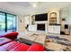 Living room with red sectional, fireplace, built-in shelving and patio access at 13506 Messina Loop # 105, Bradenton, FL 34211