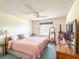 Comfortable bedroom featuring a ceiling fan, a large bed with a pink comforter, and wood furniture at 306 Friar Ct # B, Sun City Center, FL 33573