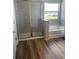 Bathroom with a glass shower enclosure, separate soaking tub, wood-look flooring, and a large window for natural light at 16013 7Th E Ave, Bradenton, FL 34212